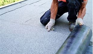 Worker Installing Flat Roll Roofing